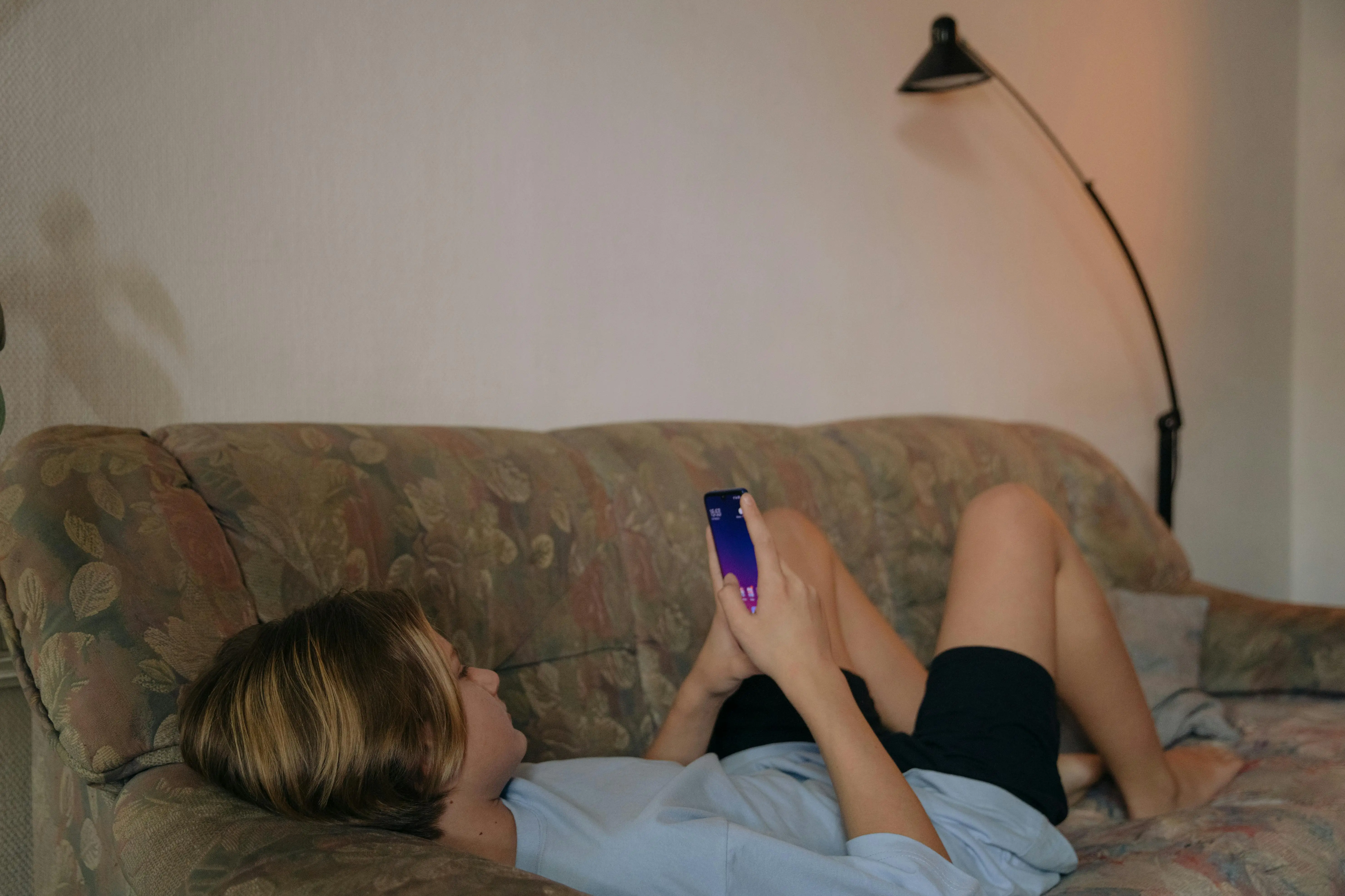 Persona relajada en un sofá usando el móvil